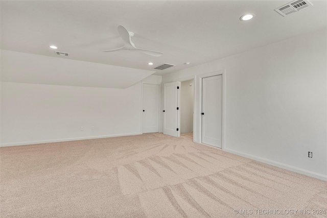 carpeted spare room with ceiling fan and vaulted ceiling