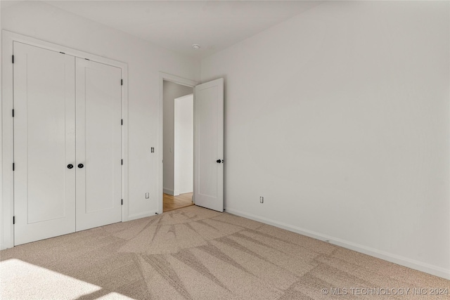 unfurnished bedroom with light carpet and a closet