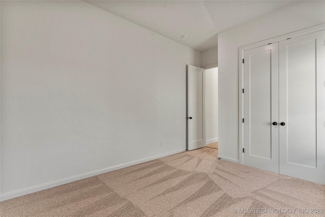 unfurnished bedroom featuring light carpet and a closet