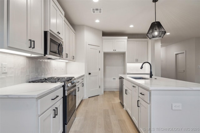 kitchen featuring hanging light fixtures, stainless steel appliances, sink, and white cabinets