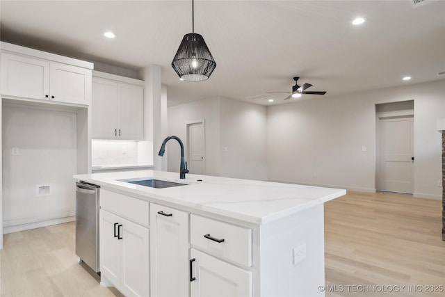 kitchen featuring sink, decorative light fixtures, a center island with sink, light stone countertops, and white cabinets