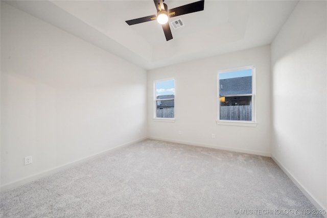 carpeted empty room with a raised ceiling and ceiling fan