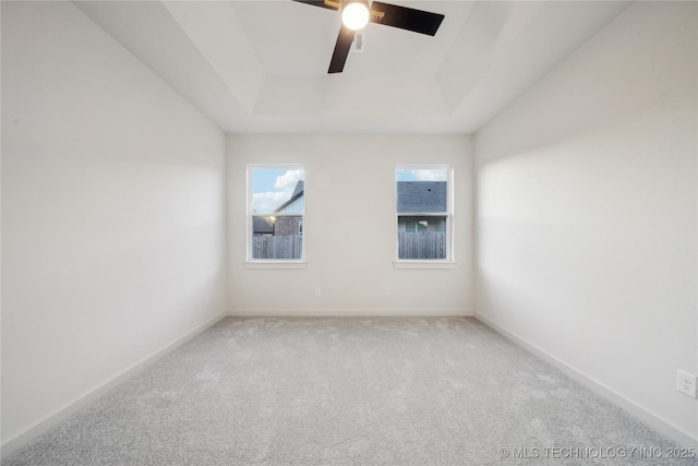 carpeted empty room featuring a raised ceiling and ceiling fan