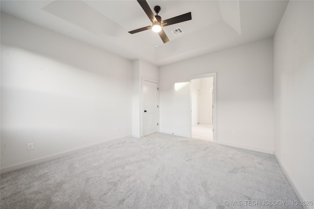 unfurnished room featuring ceiling fan, a raised ceiling, and light carpet