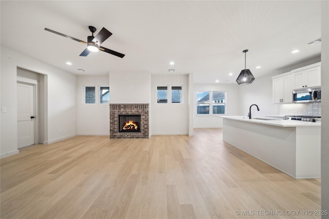 unfurnished living room featuring plenty of natural light, sink, a fireplace, and light hardwood / wood-style floors