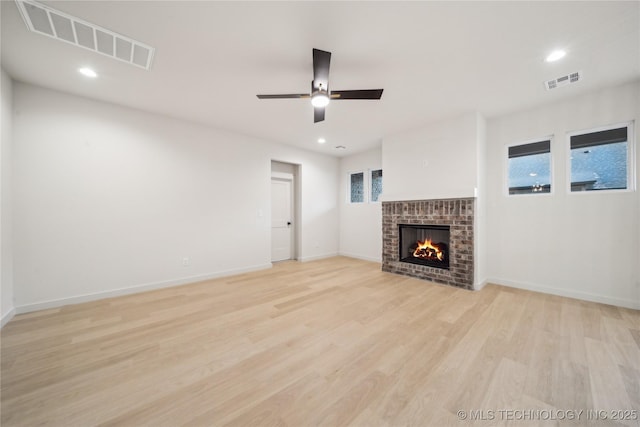 unfurnished living room featuring a fireplace, light hardwood / wood-style floors, and ceiling fan