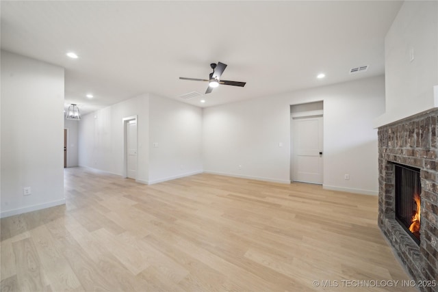 unfurnished living room featuring a brick fireplace, light wood-type flooring, and ceiling fan