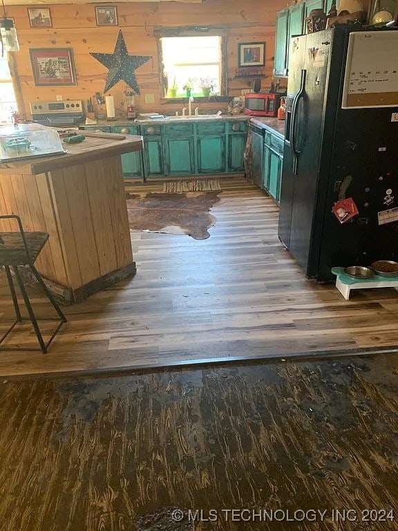 kitchen featuring black fridge with ice dispenser, green cabinets, dark wood-type flooring, and sink