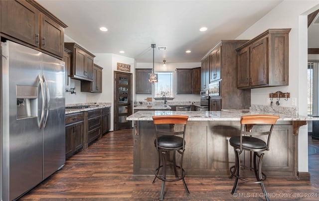 kitchen with built in appliances, dark brown cabinetry, kitchen peninsula, and pendant lighting