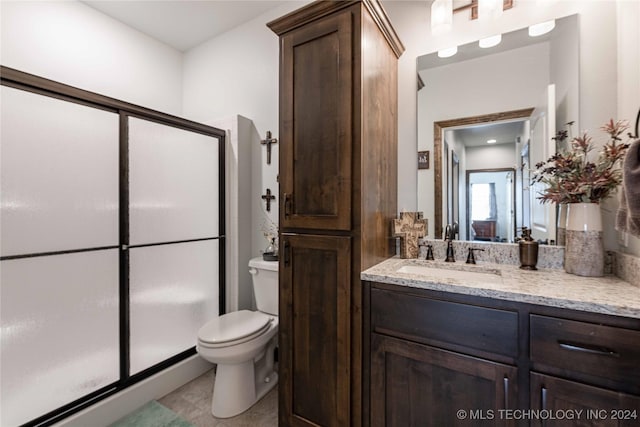 bathroom featuring vanity, toilet, and a shower with door