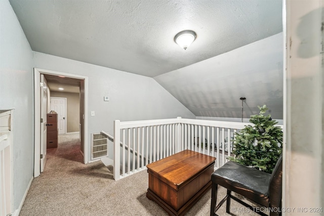 hall featuring a textured ceiling, light carpet, and vaulted ceiling