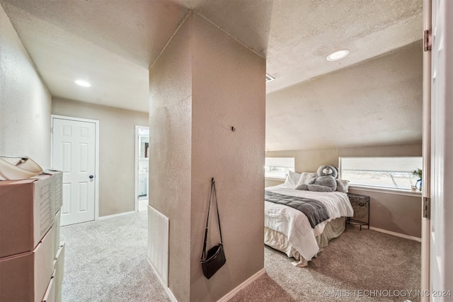 carpeted bedroom with a textured ceiling and vaulted ceiling