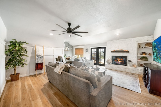 living room with a fireplace, a textured ceiling, light hardwood / wood-style flooring, and built in features