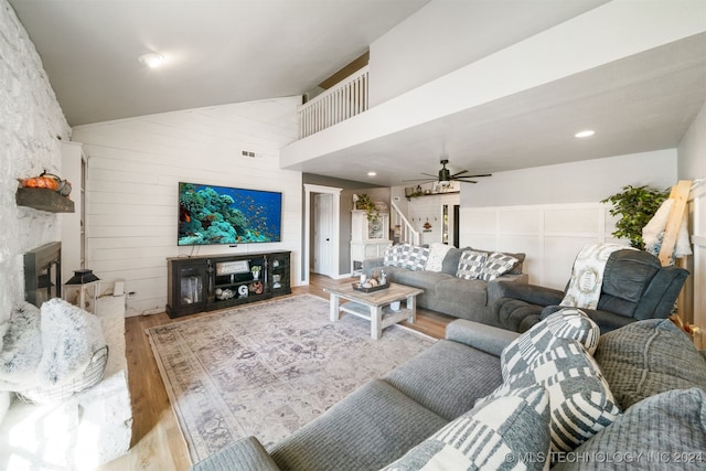 living room featuring a fireplace, light hardwood / wood-style floors, high vaulted ceiling, and ceiling fan