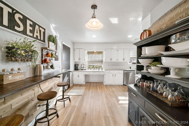 kitchen with tasteful backsplash, white cabinetry, pendant lighting, and stainless steel dishwasher