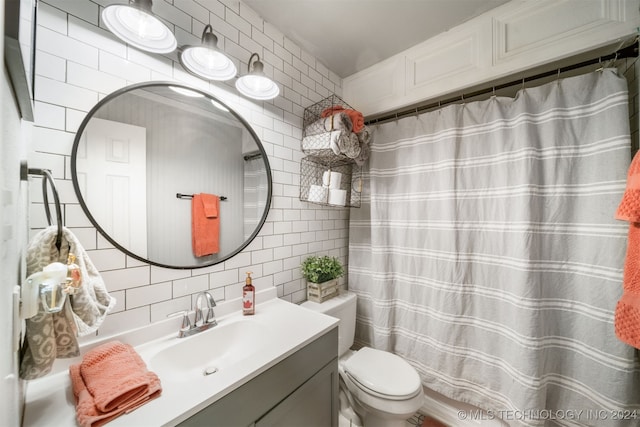 bathroom featuring vanity, tasteful backsplash, toilet, and tile walls