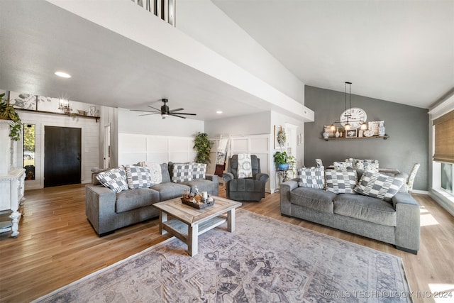 living room featuring ceiling fan with notable chandelier, light wood-type flooring, and lofted ceiling