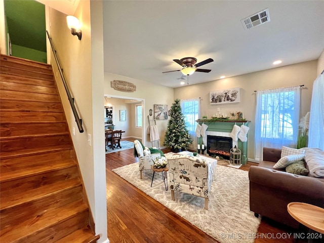 living room with a wealth of natural light, ceiling fan, a tile fireplace, and wood-type flooring