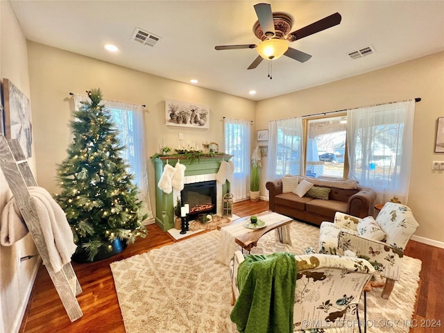 living room with a wealth of natural light, ceiling fan, and dark wood-type flooring