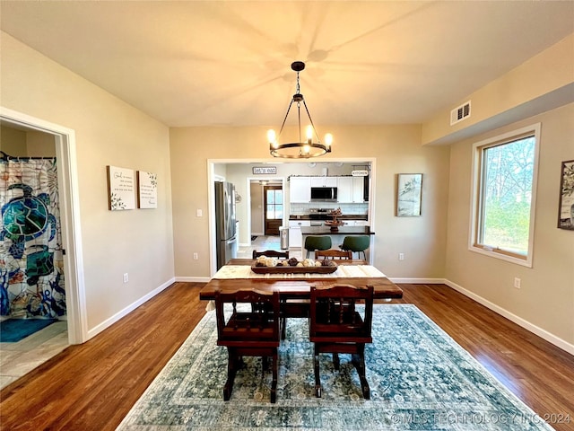 dining space featuring hardwood / wood-style floors and an inviting chandelier