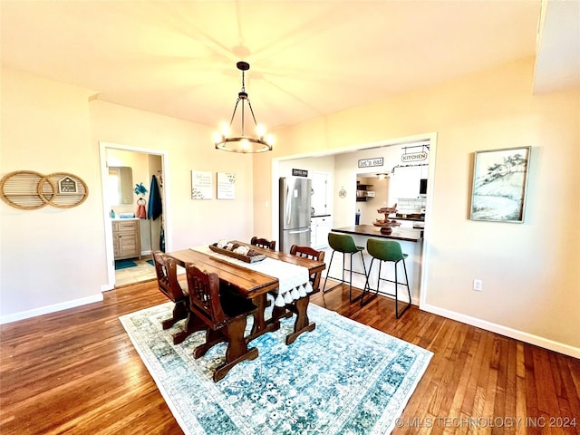 dining space featuring wood-type flooring and an inviting chandelier