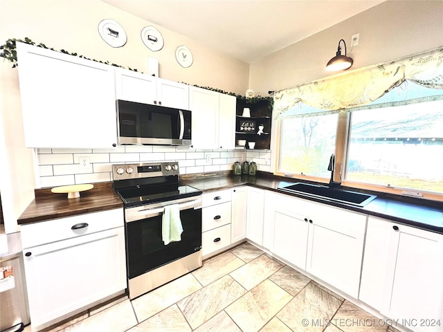 kitchen with backsplash, stainless steel appliances, white cabinetry, and sink