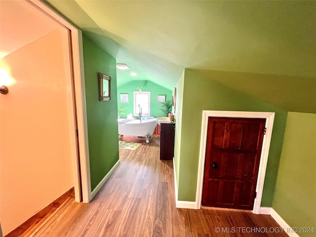 corridor featuring light hardwood / wood-style floors and lofted ceiling