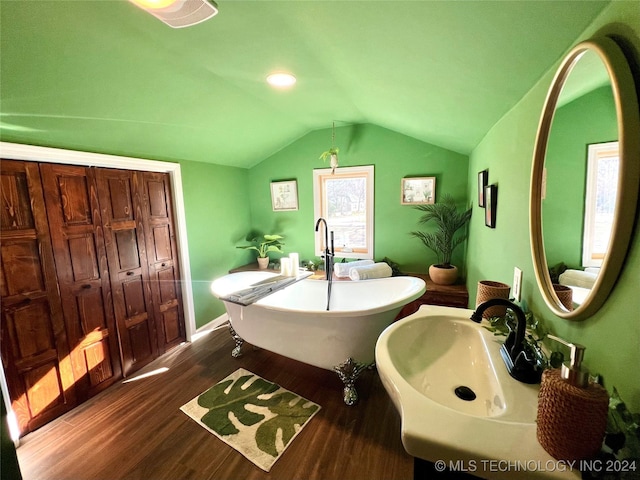 bathroom featuring sink, a bath, lofted ceiling, and hardwood / wood-style flooring