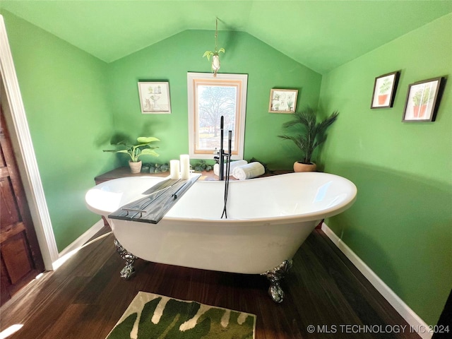 bathroom with wood-type flooring, a tub, and vaulted ceiling