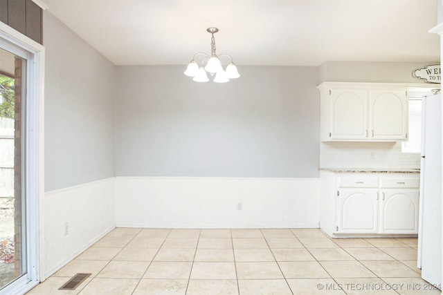 unfurnished dining area featuring light tile patterned floors and an inviting chandelier