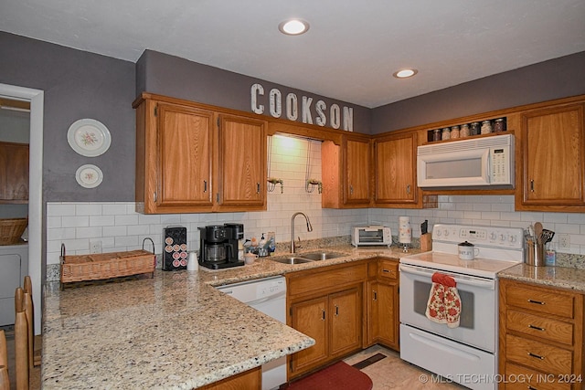 kitchen with light stone countertops, white appliances, tasteful backsplash, and sink