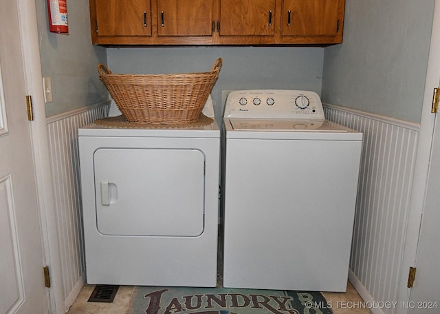 laundry room with washer and dryer, light tile patterned floors, and cabinets