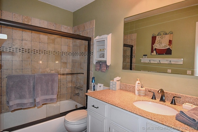 full bathroom featuring combined bath / shower with glass door, vanity, and toilet