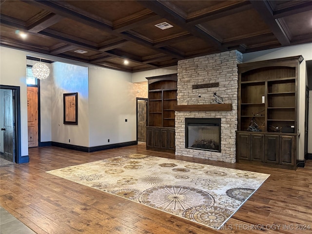 living room featuring built in shelves, dark hardwood / wood-style flooring, a fireplace, and coffered ceiling