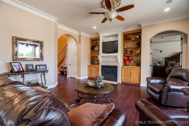 living room featuring built in features, ceiling fan, dark wood-type flooring, and crown molding