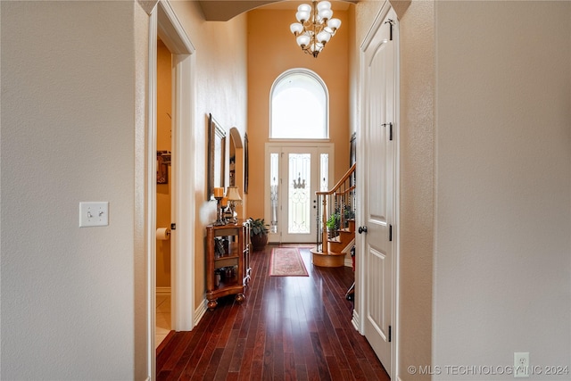 doorway with a towering ceiling, dark hardwood / wood-style floors, and an inviting chandelier