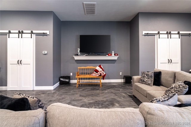 living room featuring a barn door and concrete flooring