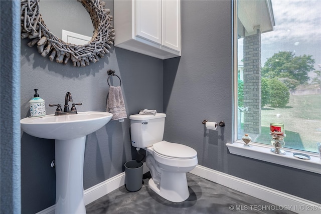 bathroom featuring concrete floors, toilet, plenty of natural light, and sink