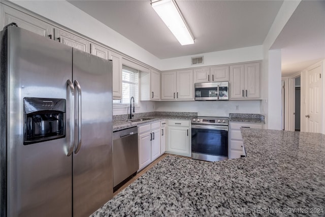 kitchen featuring sink, light stone countertops, and stainless steel appliances