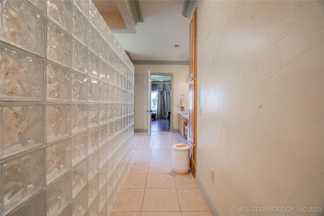 hallway featuring light tile patterned floors and crown molding