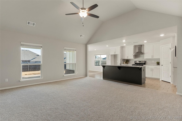 unfurnished living room featuring ceiling fan, light colored carpet, and a wealth of natural light