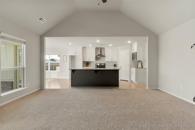 unfurnished living room with ceiling fan, light colored carpet, and vaulted ceiling