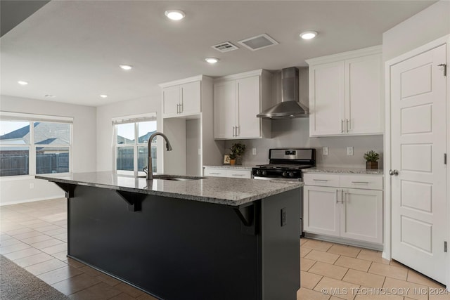 kitchen featuring gas range, a center island with sink, wall chimney exhaust hood, and sink