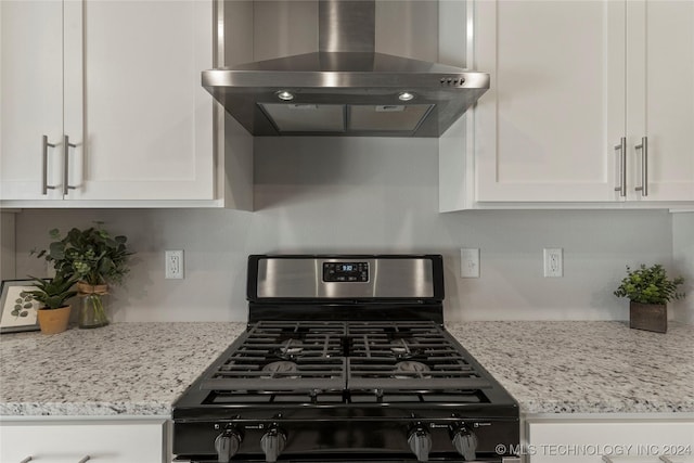 kitchen with white cabinetry, light stone countertops, wall chimney range hood, and stainless steel gas range