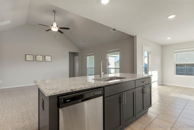 kitchen featuring ceiling fan, dishwasher, sink, light stone counters, and an island with sink