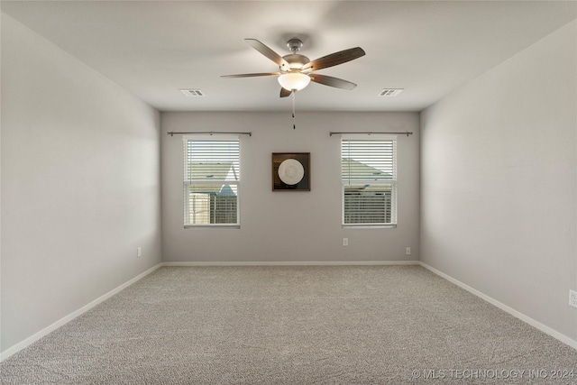 empty room with a wealth of natural light, ceiling fan, and light colored carpet