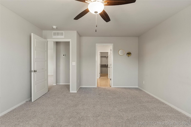 unfurnished bedroom featuring ceiling fan, light colored carpet, a spacious closet, and a closet