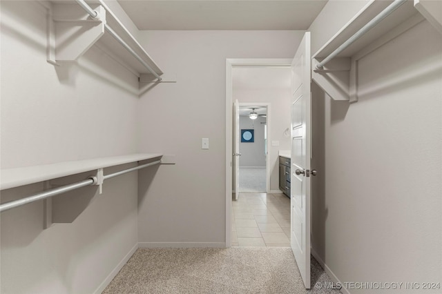 walk in closet with ceiling fan and light colored carpet