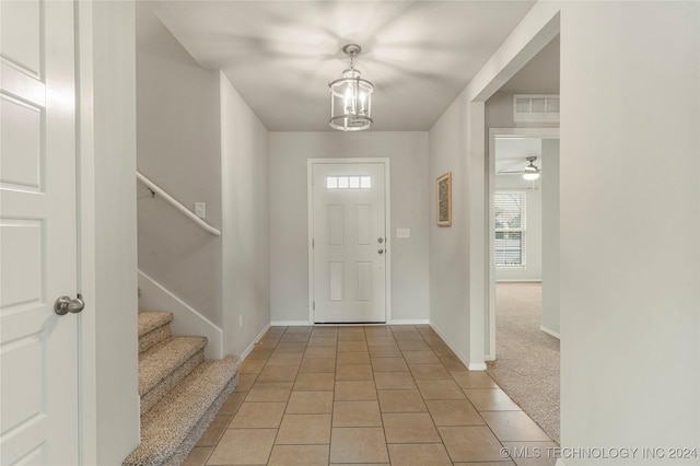 tiled entrance foyer with ceiling fan with notable chandelier