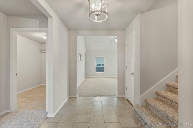 hall featuring light colored carpet and an inviting chandelier